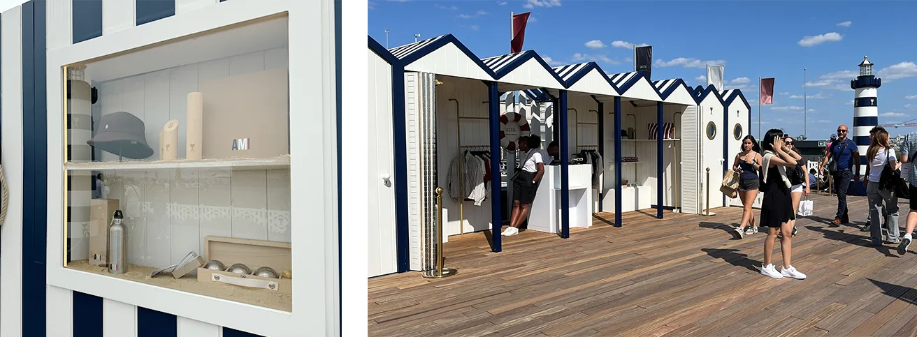 Vitrine d'objets dans une cabine AMI et rangée de cabines rayées avec visiteurs et phare au fond