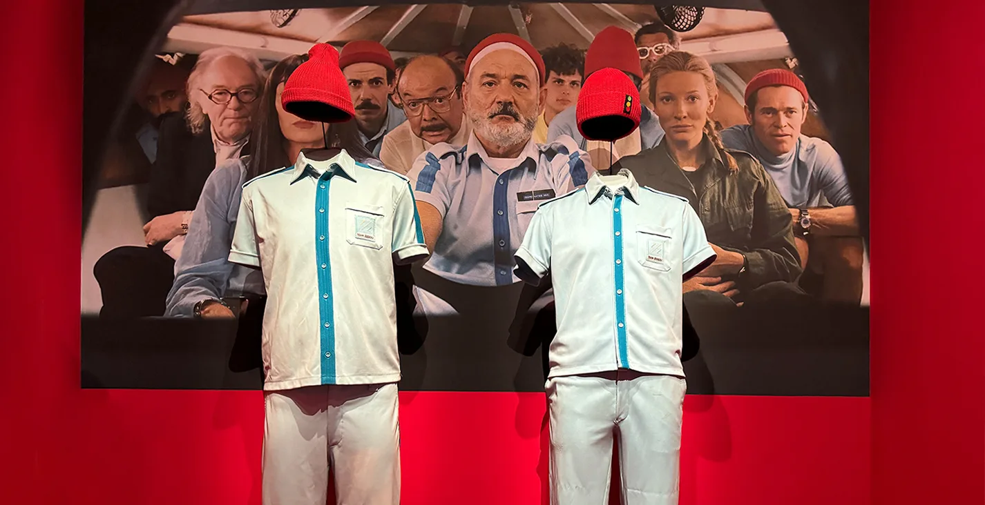 Costumes bleu et blanc à bonnets rouges de La Vie aquatique devant une photo de l'équipage du film