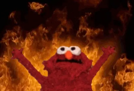 Elmo les bras levés devant un mur de flammes