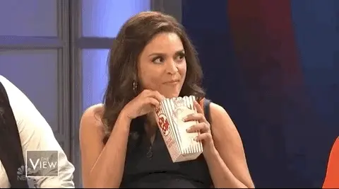 Femme mangeant du popcorn avec gourmandise sur un plateau de télévision